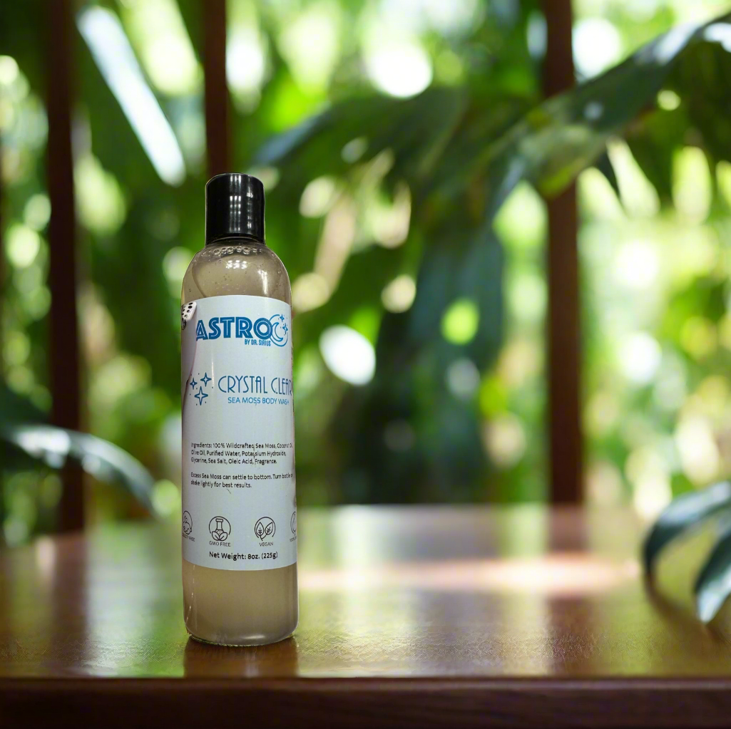 Astro Sea Moss Body Wash bottle on wooden surface with green plants background, natural skincare product.